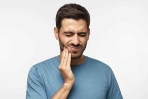 Person experiencing severe toothache and seeking immediate relief at home