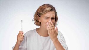 Person frustrated by persistent bad breath even after brushing teeth.
